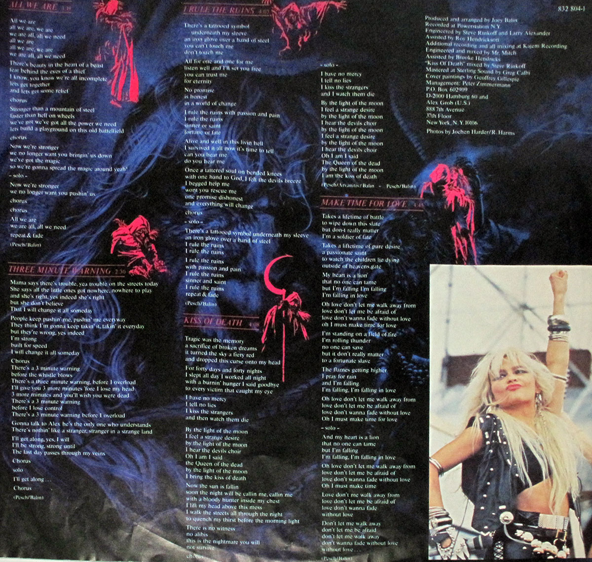 Custom inner sleeve of Warlock’s 1987 album Triumph and Agony, West German Vertigo pressing. The design presents a black background overlaid with red spectral illustrations of skeletal and demonic figures, paired with printed song lyrics for Side One including All We Are, Three Minute Warning, I Rule the Ruins, Kiss of Death, and Make Time for Love. Production credits are listed in the upper right. At the bottom right corner, a full-color band photograph shows Doro Pesch live on stage, raising her arm triumphantly in a leather-studded outfit.